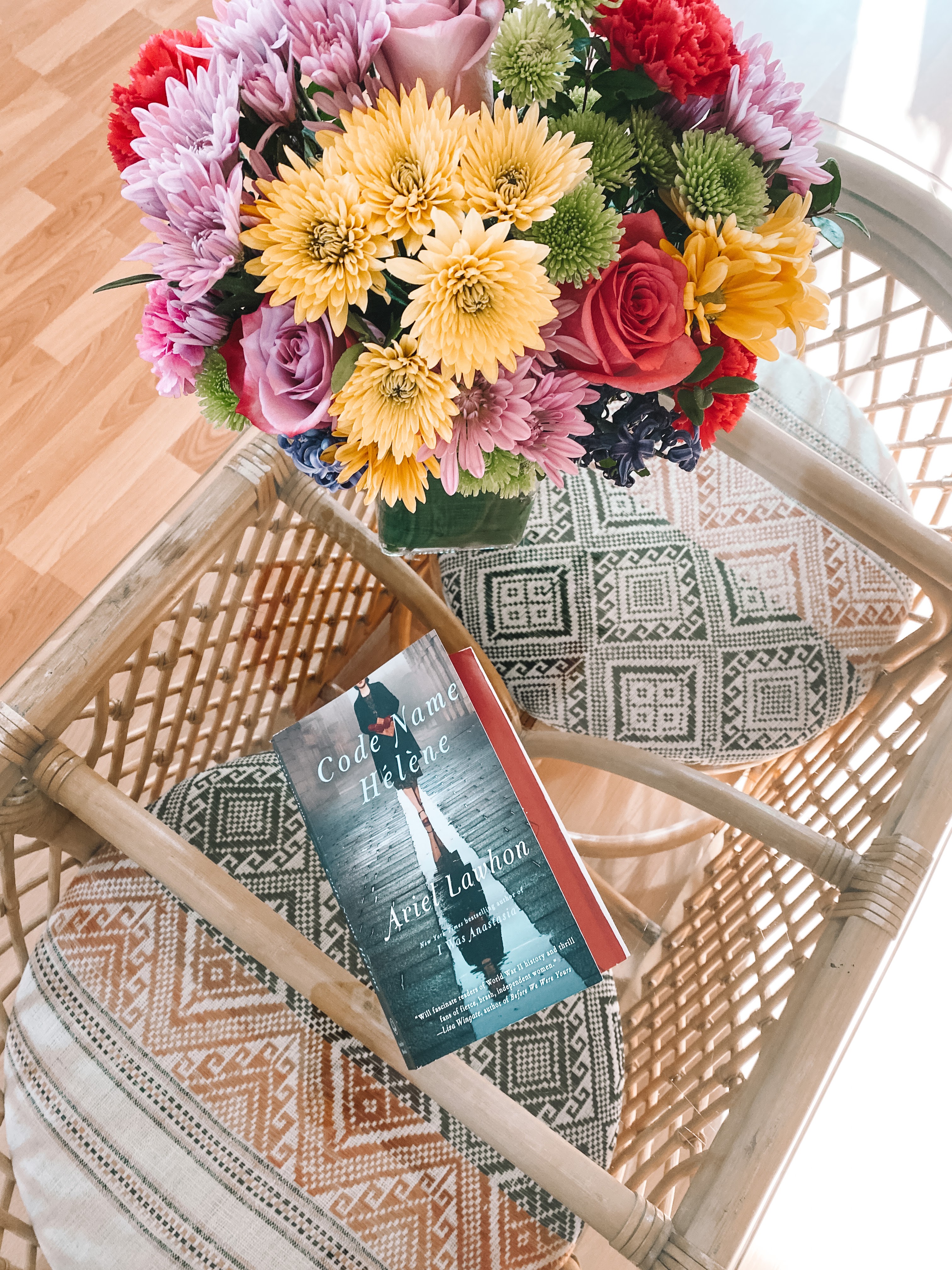Book on glass top table with a bouquet of flowers. 